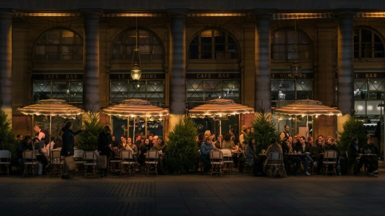 Terrasse de café animée sous des parasols rayés le soir